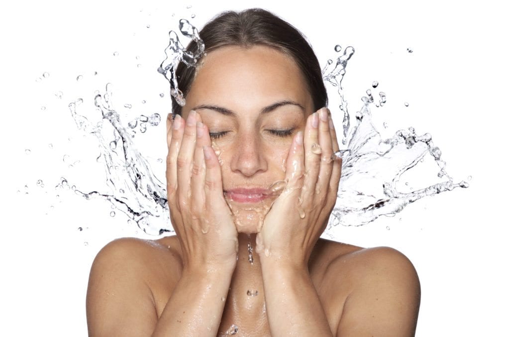 Beautiful wet woman face with water drop. Close-up portrait on white background