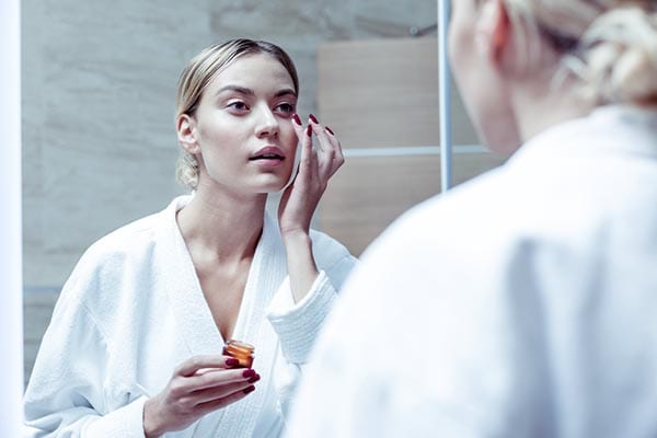 woman putting some nourishing cream under her eyes