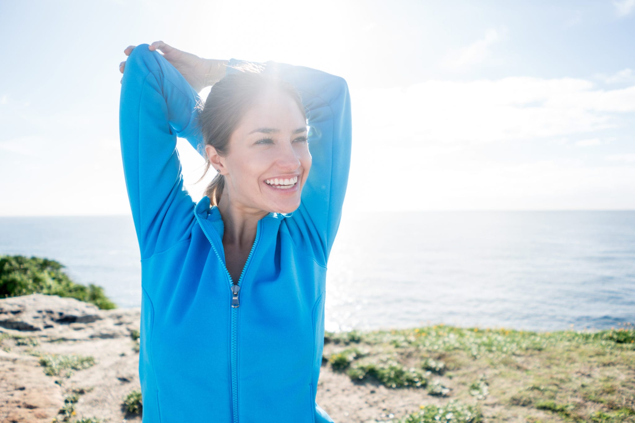 Happy young woman stretching her arms outdoors while enjoying the scenery