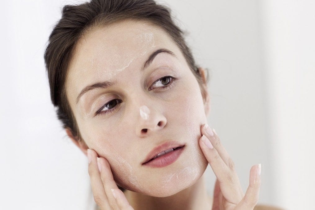 close-up of a young woman applying moisturizer on her face